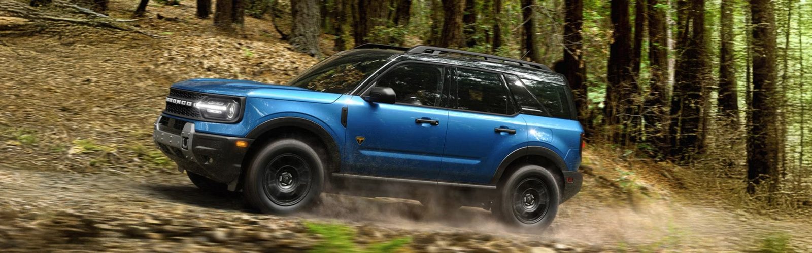 Blue Ford Bronco Sport driving on a wooded trail