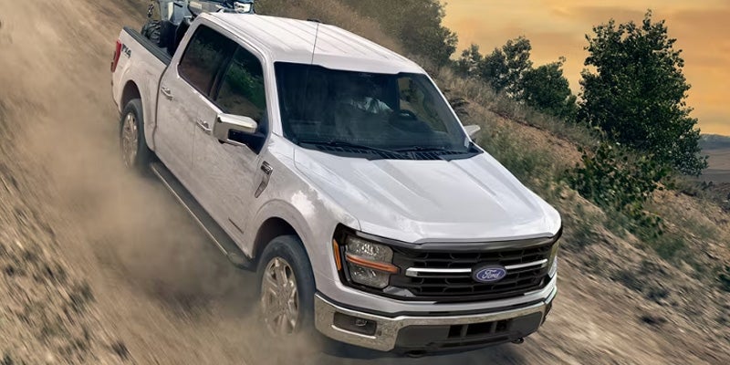 White Ford F-150 driving up a dirt road