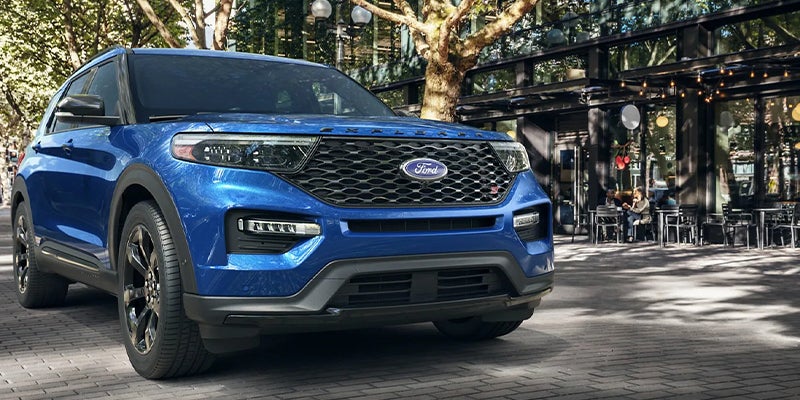 Blue Ford Explorer ST SUV parked in an urban setting, showcasing sporty styling, black exterior accents