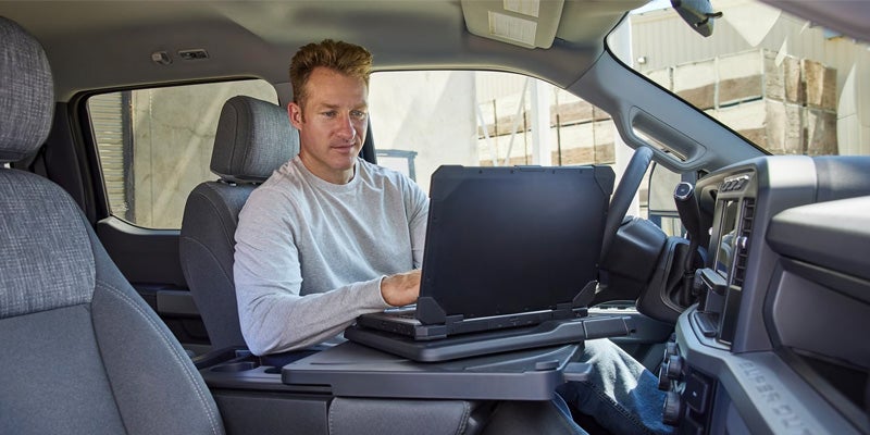 Ford Super Duty interior featuring a fold-down work surface with a laptop, highlighting the truck's mobile office functionality
