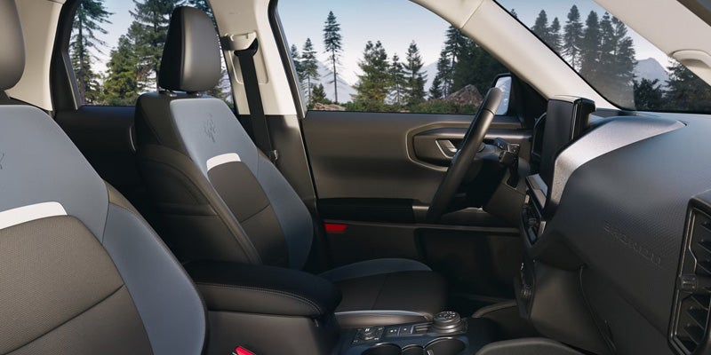 Front cabin interior of an SUV showing black and gray front seats, center console, steering wheel
