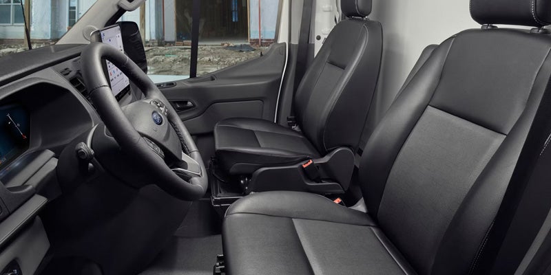 Black leather driver and passenger seats inside a Ford van, with a steering wheel and a large mounted tablet.