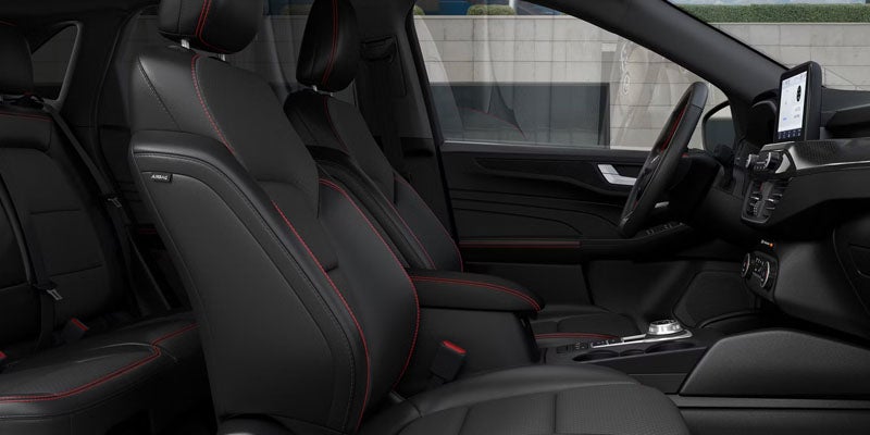 Interior of a car with black leather seats and red stitching, showing the front passenger, driver, and back seats.