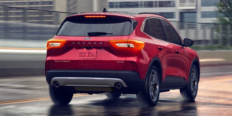 Rear view of a red Ford Escape Platinum SUV driving on a wet road, possibly in motion.
