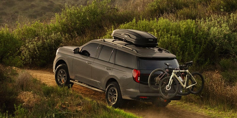 Ford Expedition SUV driving on a rugged trail with roof-mounted cargo carrier