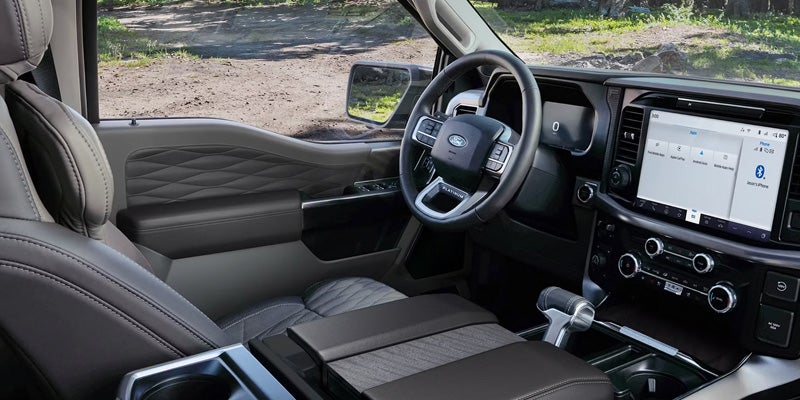A sleek, dark gray truck interior, with a touchscreen, steering wheel, and quilted leather seats.