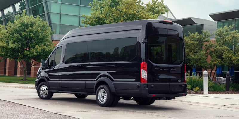Black high-roof passenger van parked on a city street, shown from the rear three-quarter angle